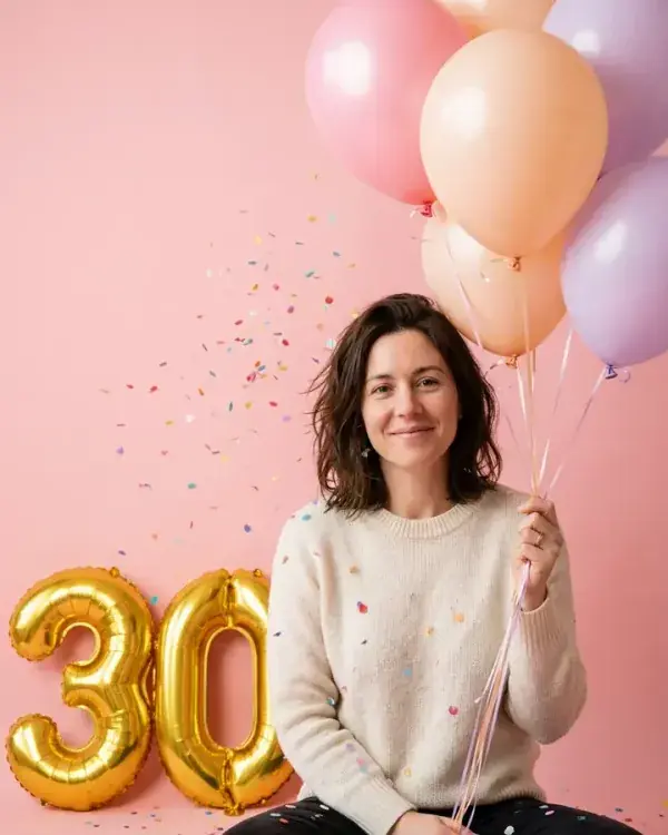 A birthday photo of a woman with pastel balloons and gold 3 and 0 number balloons