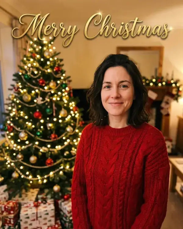 A Christmas card of a woman in a red sweater beside a decorated tree, with Merry Christmas in gold