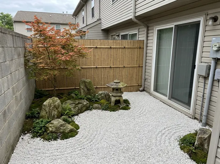 The same patio as a Japanese zen garden: raked white gravel, mossy stones, a red-leaved maple, a bamboo screen and a stone lantern