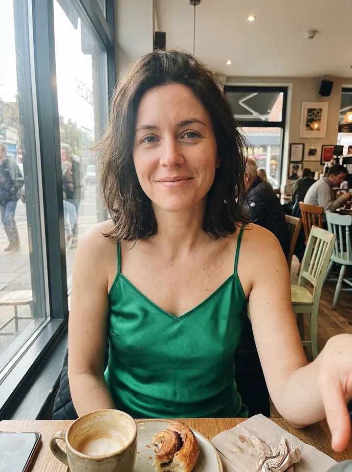 The woman in the same cafe wearing the green satin slip dress from the product photo