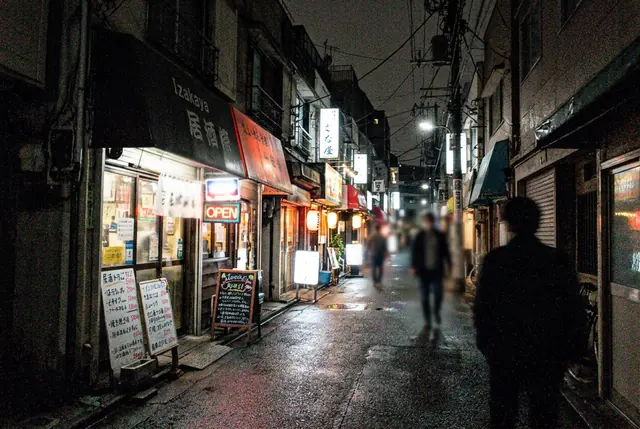 A grainy night photo of a narrow street of small bars and shops, covered in colored speckles (made with the model)