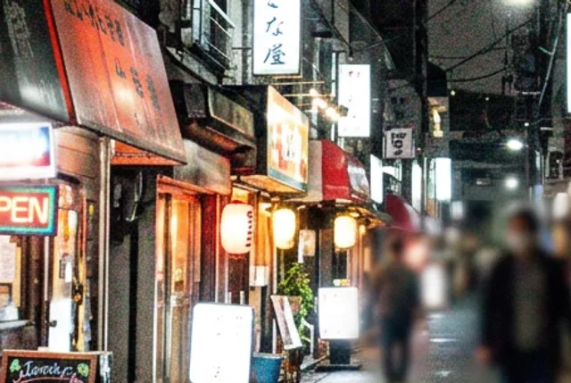 Close-up of the lit shop fronts in the grainy night photo, speckled with noise