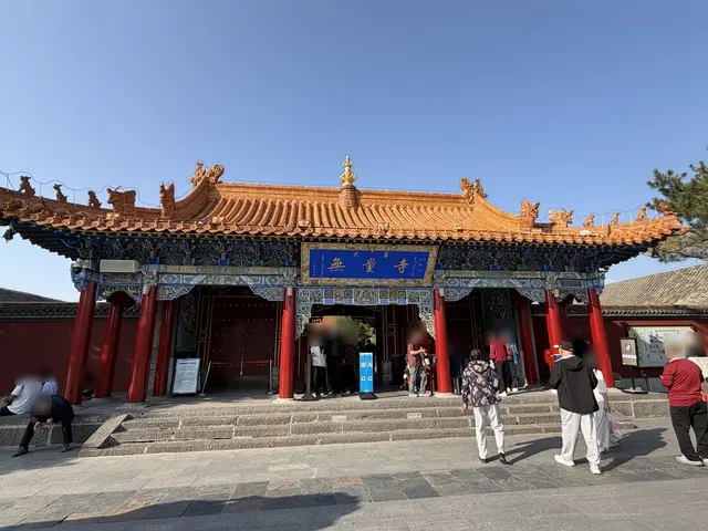 The owner's own photo of the gate of Dazhao Temple: orange glazed roof, blue plaque and red columns, with visitors (faces blurred)