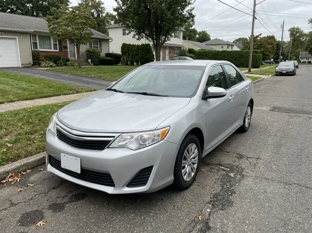 A phone photo of a plain silver sedan with a blank license plate, parked on a quiet suburban street (made with the model)