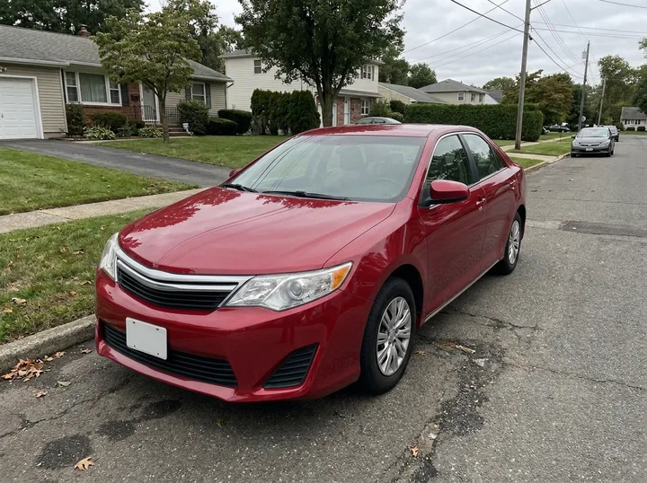 The same sedan repainted a glossy deep red on the same street