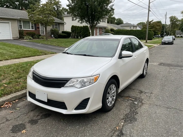 The same sedan in a satin pearl white with a soft sheen on the same street