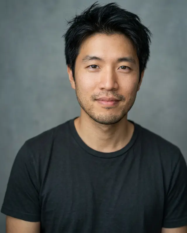 The man in a charcoal t-shirt against a gray-blue backdrop, looking into the camera