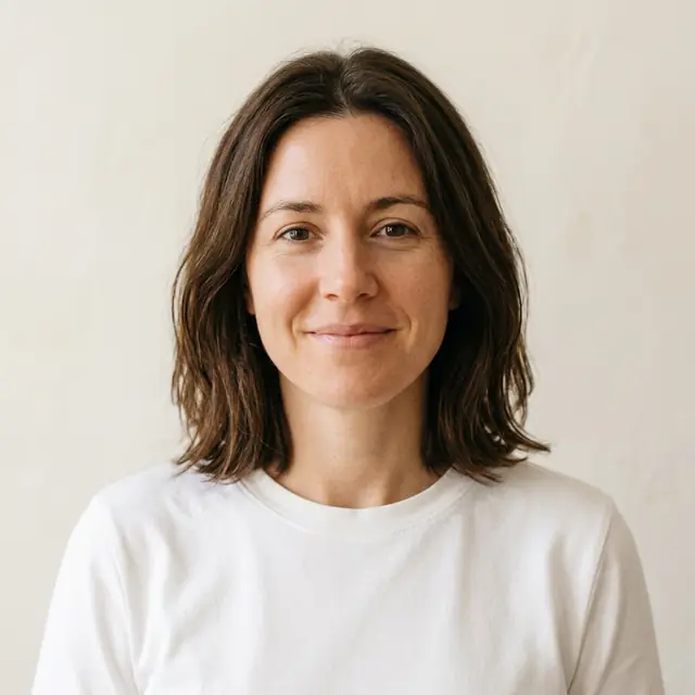A team-page headshot of the woman in a white t-shirt on an off-white background