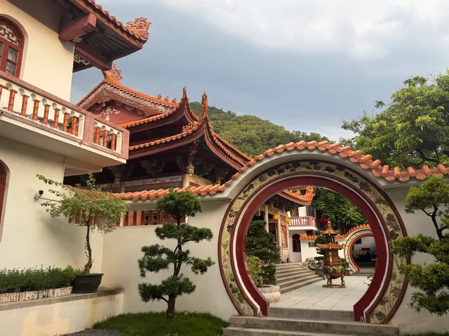 Our own travel photo: a temple courtyard with a round moon gate, orange roof tiles, bonsai and an incense burner