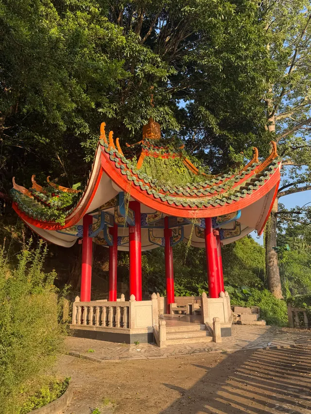 Our own travel photo: a red-pillared pavilion with a curved green-tiled roof under tall trees