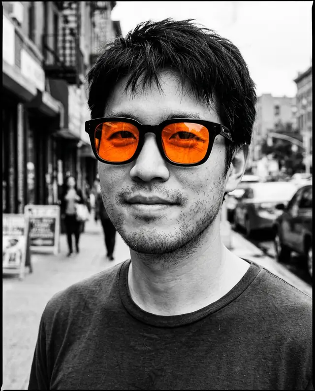 A black-and-white close-up of the same man wearing sunglasses with bright orange lenses