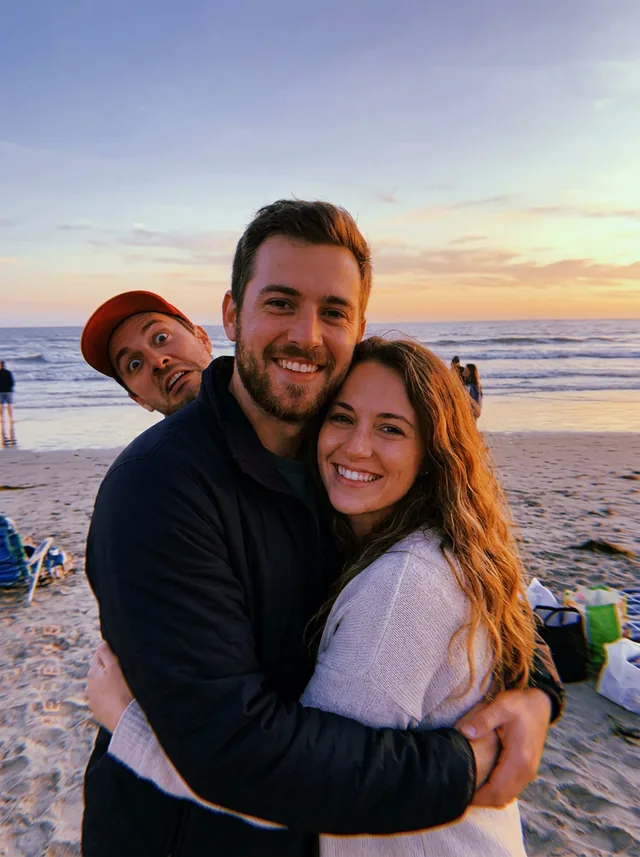 A couple hugging on a beach at sunset, with a man in a red cap pulling a face right behind them (made with the model)